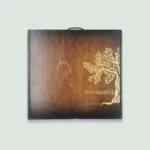 The exterior of a wooden gift box with a dark finish. The box features a golden tree logo and the text "Gourmet Groceries" along with the website "shop.gourmetgroceries.com."
