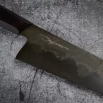 Detailed shot of the stunning Damascus steel pattern on the blade of the Handmade Gyoto Knife Cinyras, showcasing the unique craftsmanship.
