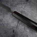 Focused image of the sharp blade of the Handmade Gyoto Knife Cinyras, emphasizing its high-quality construction and cutting performance.