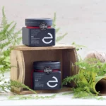 Two bottles of Eulogia’s Premium Organic Fir Honey surrounded by lush greenery, showcasing the product’s natural origin