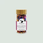 Artistic display of the Flamme Orientale edible flowers bottle, featuring a mix of delicate, brightly colored petals in a clear jar against a neutral background.