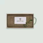 The inside of a Gourmet Groceries gift box, with products under a linen wrapping, a card, and an olive leaf.