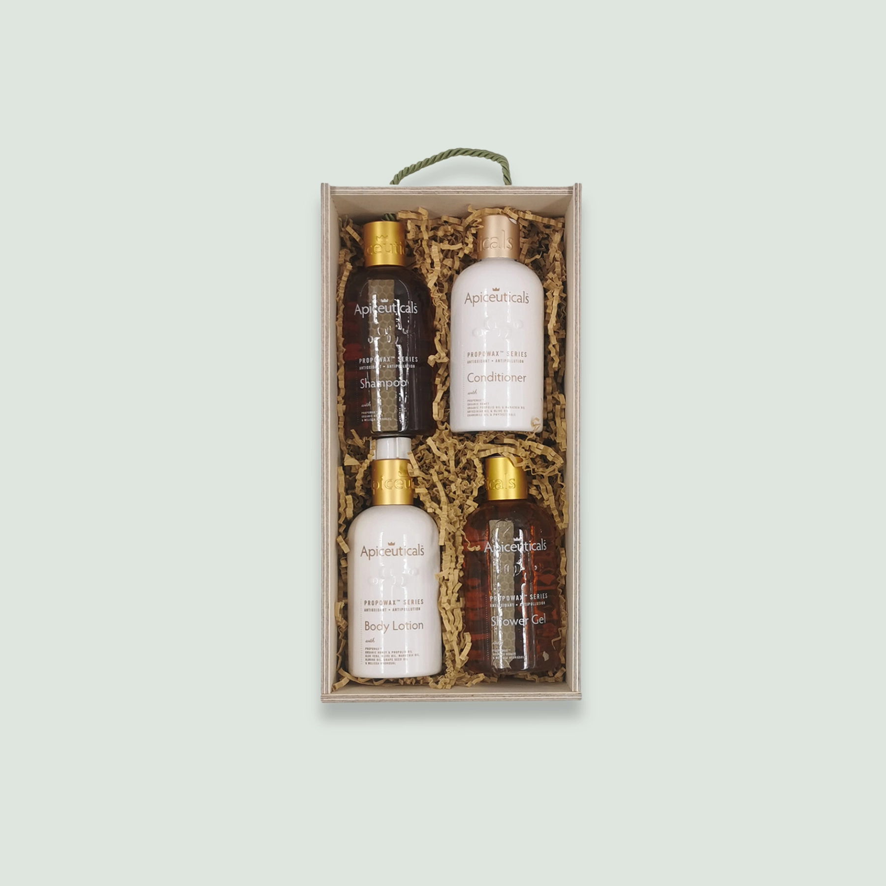 A wooden gift box containing Apiceuticals hair and skincare products. The box includes shampoo, conditioner, body lotion, and shower gel. The products are arranged in wood wool for an elegant presentation.