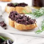 Marfuga Black Olive Spread spread on crispy bruschetta, perfect for Mediterranean appetizers.