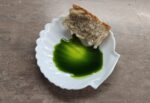 sparta Greek Olive Oil tasting with a piece of bread in a white plate seeing its dark green colour
